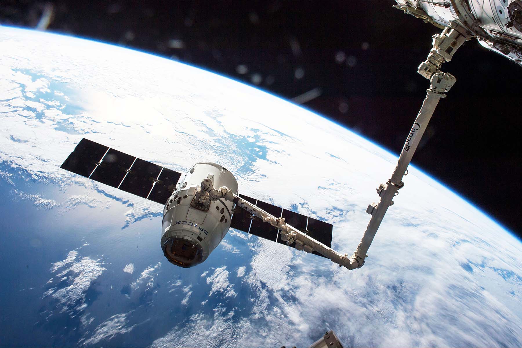 Canadarm and SpaceX Dragon spacecraft above Earth